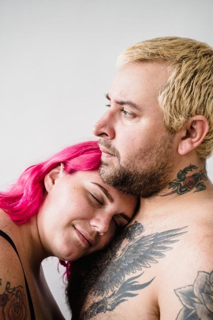 Close-up shot of an affectionate, tattooed couple embracing in a studio setting.