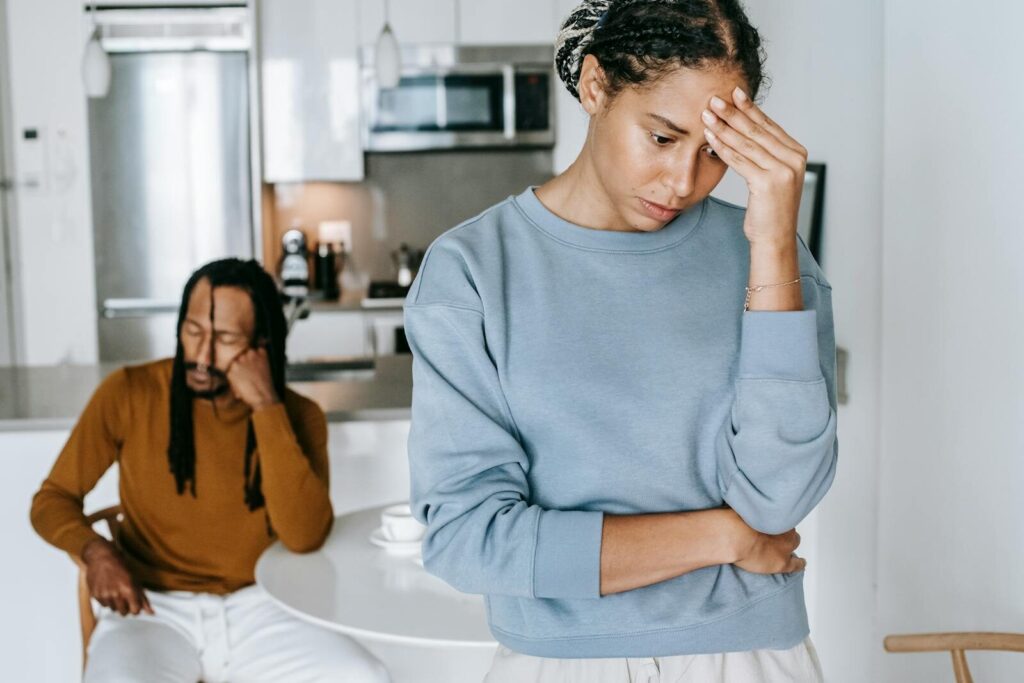A young couple expressing emotions of conflict and discontent in a modern kitchen setting.