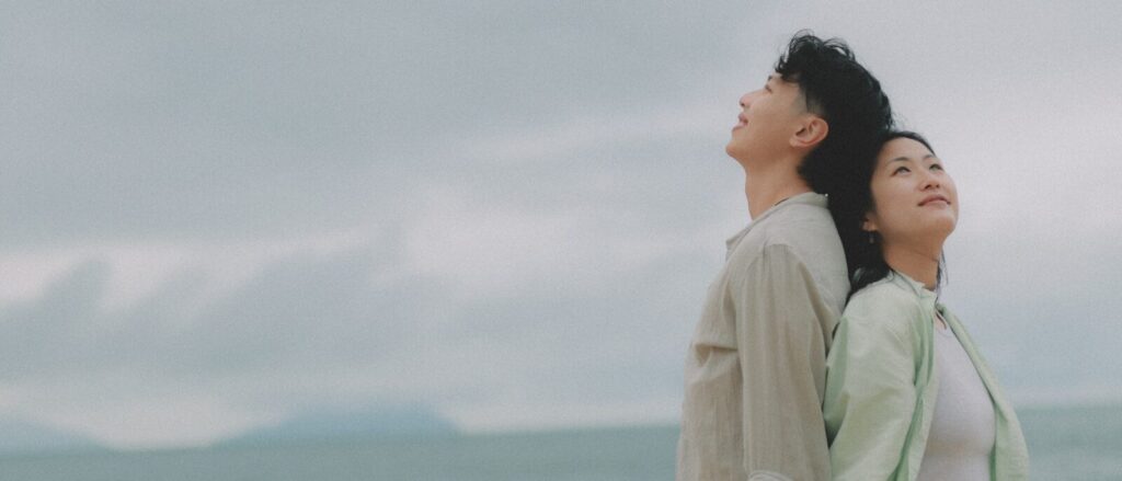 Couple looking up at the sky by the ocean.