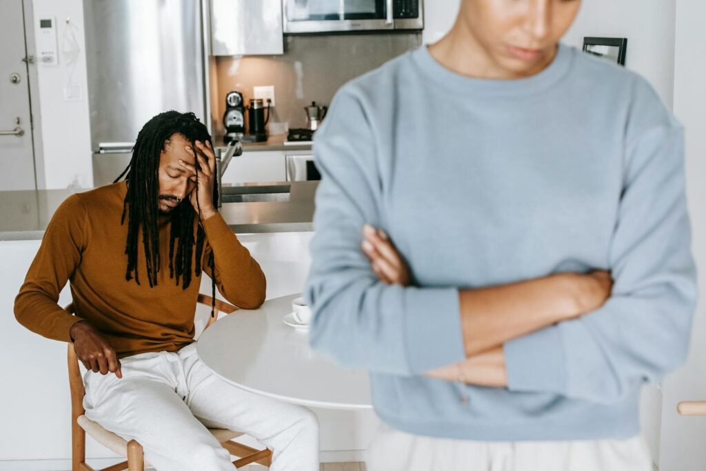 Young black guy sitting at table and having conflict with lady in light room