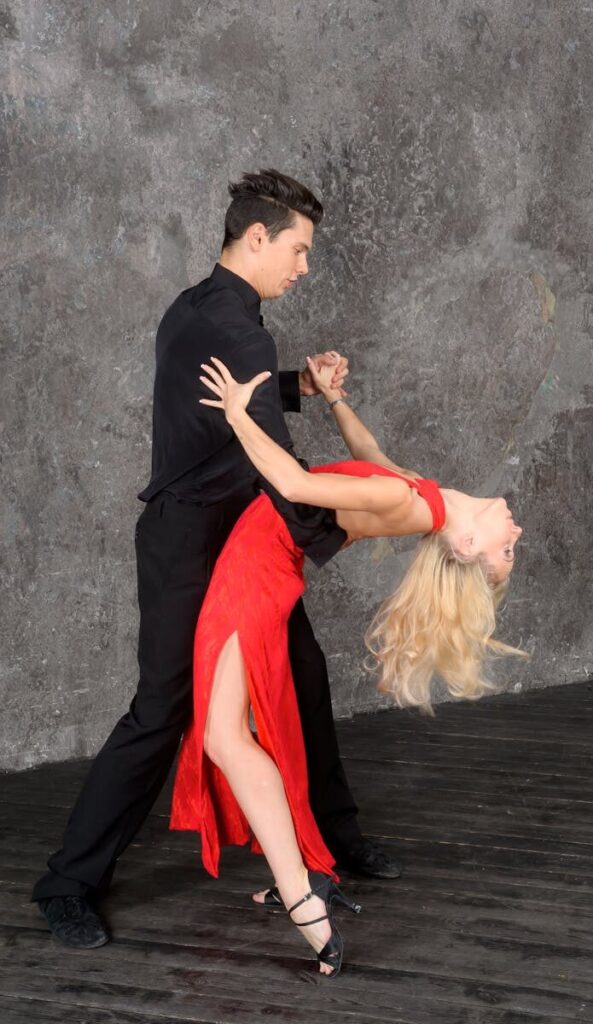 Passionate couple performing a ballroom dance in a striking red and black ensemble.